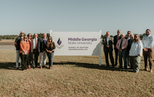 MGA and city of Cochran representatives pose for a photo next to th new MGA sign at the Cochran Airport. 